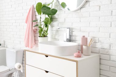 Lavabonun yanındaki çekmecelerde saç derisi masaj aletleri olan bir banyo.