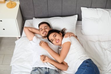 Sevgi dolu genç bir çift evde yatakta yatıyor.