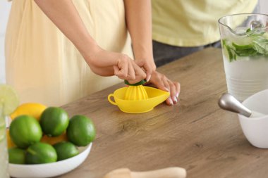 Genç çift mutfakta mojito için limon suyu sıkıyor, yakın plan.