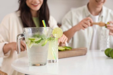 Mutfakta mojito için taze limon kesip sıkan mutlu genç çift, yakın plan.