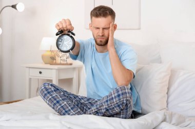 Evde uykusuzluk çeken saatli genç bir adam.
