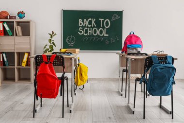 Modern sınıfta okul sıraları, sırt çantaları ve tahtalar