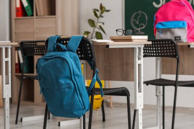 Modern sınıfta sırt çantalı okul masaları, yakın çekim.