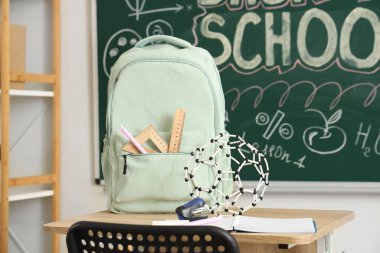 Sırt çantalı ve defterli okul masası açık sınıfta.