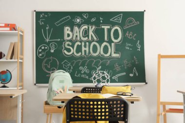 Sırt çantalı ve defterli okul masası açık sınıfta.