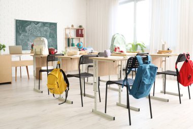 Sırt çantalı okul sıraları ve açık renkli sınıflarda kara tahta.