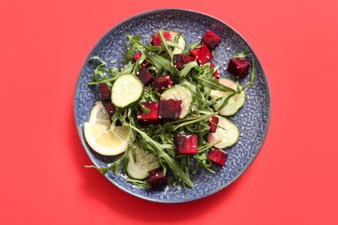 Kırmızı arka planda pancar ve salatalıklı taze salata.