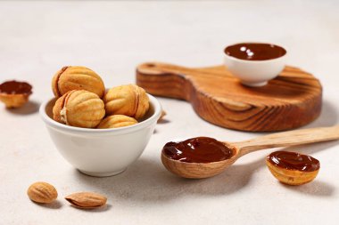 Lezzetli ceviz şekilli kurabiyeler, kaynamış süt ve beyaz grunge masasında badem.