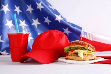 Kırmızı kapaklı lezzetli bir burger, beyaz arka planda Amerikan bayrağı. Amerikan Bağımsızlık Günü kutlamaları
