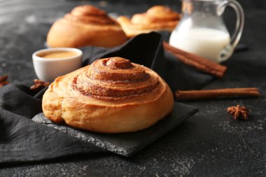 Yıldız anasonlu tarçınlı çörekler ve siyah arka planda bir sürahi süt.