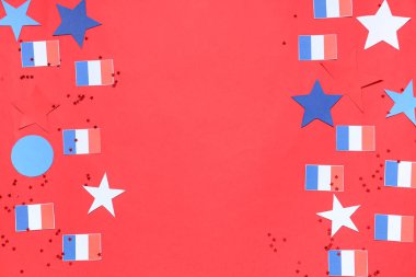 Kırmızı arka planda Fransız bayrakları, yıldızlar ve konfeti. Bastille Günü kutlamaları