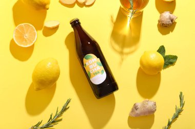 Sarı arka planda limon ve zencefilli bir şişe lezzetli kombu çayı.