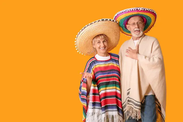 stock image Mature couple in sombrero hats on yellow background