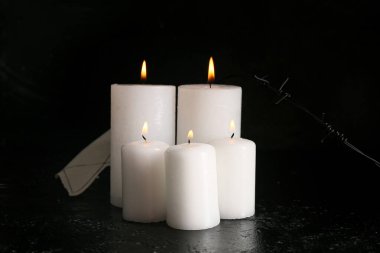 Siyah arka planda dikenli telle mum yakmak. Anma Günü