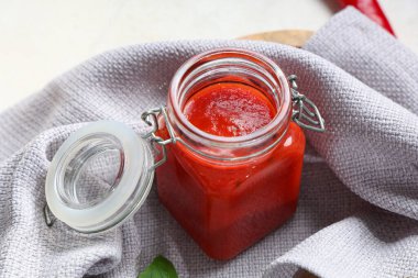 Beyaz arkaplanda bir kavanoz domates sosu, yakın plan.