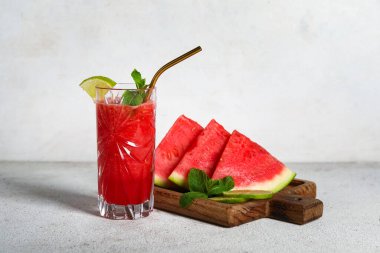 Bir bardak taze karpuz suyu, beyaz arka planda limon ve nane.