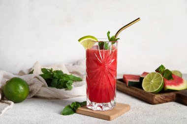 Bir bardak taze karpuz suyu, beyaz arka planda limon ve nane.