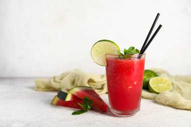 Bir bardak taze karpuz suyu, beyaz arka planda limon ve nane.