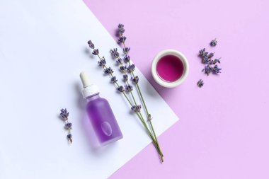 Renkli arka planda çiçekler, şişe ve bir kase lavanta yağı