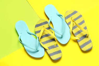 Sarı arka planda farklı tarz parmak arası terlikler.