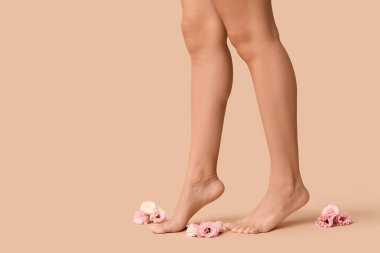 Kahverengi arka planda güzel Eustoma çiçekleri olan genç bir kadının bacakları.