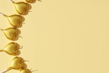 Sarı arka planda kalp şeklinde birçok doğum günü mumu var.