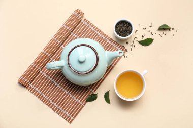 Bej arka planda kurumuş yapraklı çay fincanı ve çaydanlık.