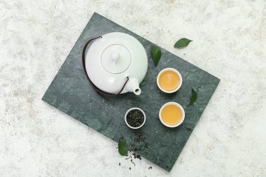 Beyaz arka planda kurumuş yapraklı sıcak çay kaseleri ve çaydanlık.