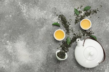 Kase ve çaydanlık dolusu sıcak çay ve gri arka planda kurumuş yapraklar.