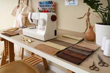 Atölyedeki terzi masasında kumaş örnekleri olan dikiş makinesi.