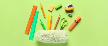 Yeşil arka planda farklı okul kırtasiyesine sahip kalem kutusu, üst görünüm