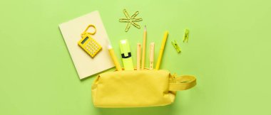 Yeşil arka planda farklı okul kırtasiyesine sahip kalem kutusu, üst görünüm