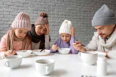 Ill family eating soup at table in kitchen