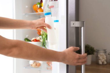 Dolaptan taze süt alan kadın eller. Yakın çekim.