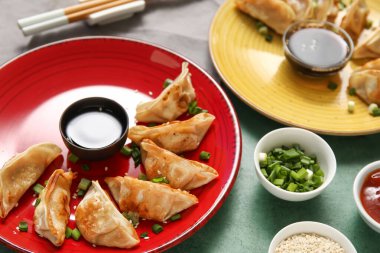 Kızarmış Japon gyoza tabakları ve yeşil arka planda bir kase soya sosu.