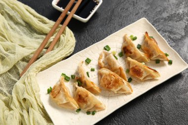 Kızarmış Japon gyoza tabağı ve siyah arka planda soya sosu.