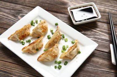Kızarmış Japon gyoza tabağı ve ahşap arka planda soya sosu.