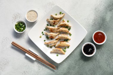 Kızarmış Japon gyoza tabağı ve grunge arkaplanda soslar.