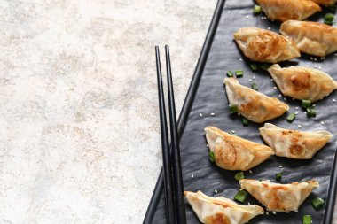 Kızarmış Japon gyozası ve gri arkaplanda yeşil soğan.