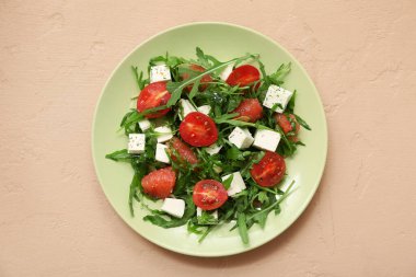 Bir tabak taze sebze salatası, beyaz peynirli, domatesli, greyfurtlu ve roka arkaplanlı.