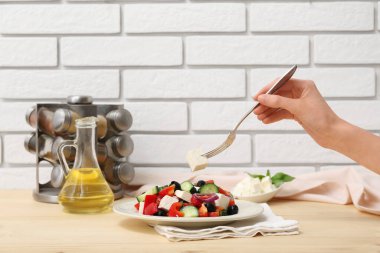 Çatallı kadın eli ve ahşap masada sağlıklı sebze salatası tabağı.