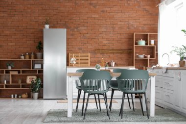 Modern mutfak, yemek masası, buzdolabı ve raf ünitesi.