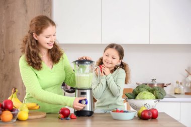 Anne ve küçük kız mutfakta sağlıklı meyve püresi yapıyorlar.