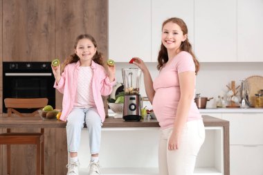 Anne ve küçük kızı mutfakta meyveleri harmanlıyor.