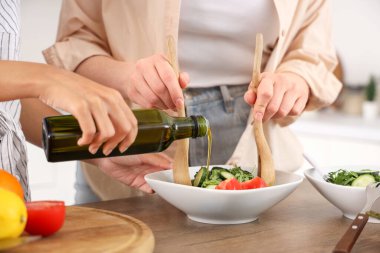 Genç kadınlar mutfakta salata yapıyor, yakın plan.