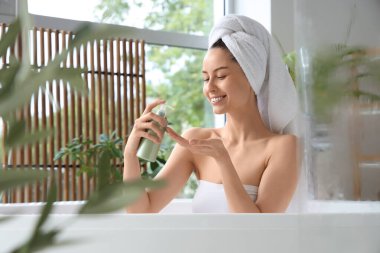 Bir şişe şampuanla evde banyo yapan güzel, genç ve mutlu bir kadın.