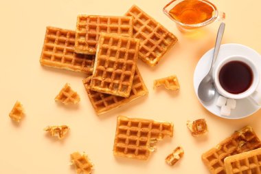Lezzetli Belçika waffleları, tatlı bal teknesi ve sarı arka planda bir fincan kahve.