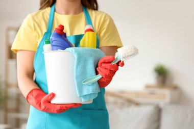 Odasında bir kova temizlik malzemesi olan kadın hademe, yakın plan.