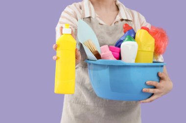 Leylak arka planında temizlik malzemeleri olan kadın hademe, yakın plan.