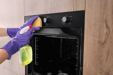 Mutfakta sünger ve sprey şişe temizleme fırını olan kadın, yakın plan.